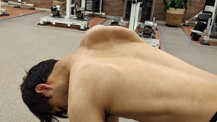 肩甲骨を剥がす動きを表現する男性